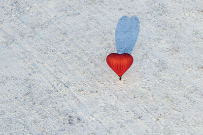 High angle view of heart shape hot air balloon flying over snowy land