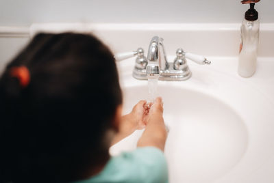 Cute girl washing hand at sink