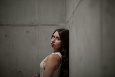 Portrait of young woman standing against wall