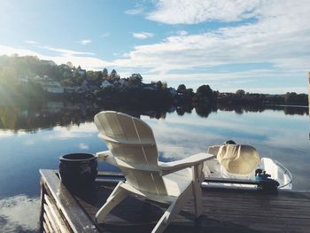 Empty deck chair on pier by lake