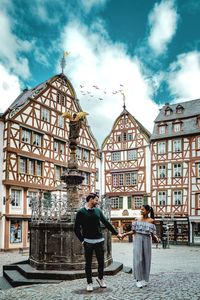 Smiling couple holding hands while standing on street in city