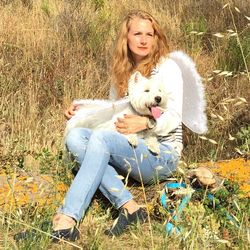 Portrait of woman with dog sitting in grass