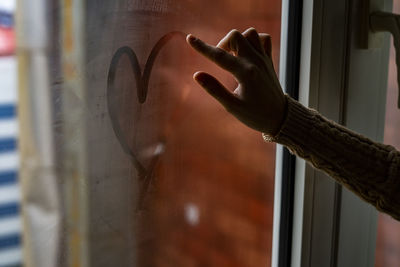 Hand drawing a heart with your finger on the window.