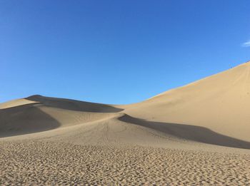 Scenic view of desert against clear blue sky