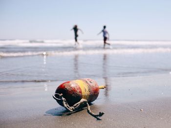 Old buoy against playful friends at beach