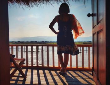 Rear view of a woman standing against railing