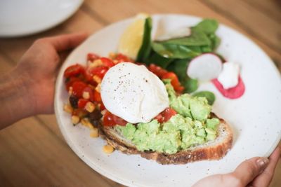 Close-up of hand holding salad in plate