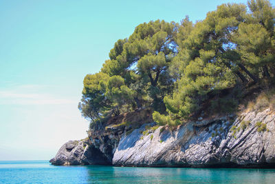 Rock formation by sea against sky