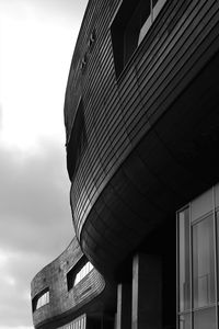 Black and white low angle view of modern architecture against cloudy sky