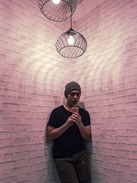 Full length of man standing against wall and holding a cactus. 