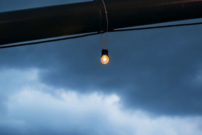 Low angle view of illuminated light bulb against sky at dusk