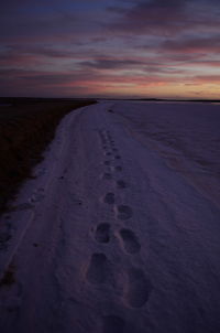 Footprints on beach at sunset