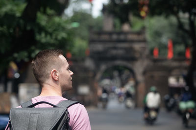 Traveler walking on busy asian street. rear view of man with backpack in old quarter in hanoi.