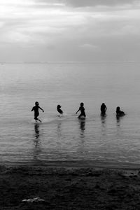 Silhouette people on beach against sky