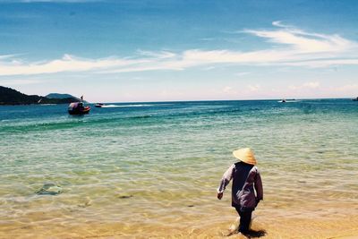 Rear view of man standing at beach against sky