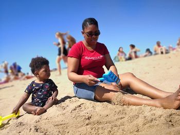 Happy siblings on beach against clear sky