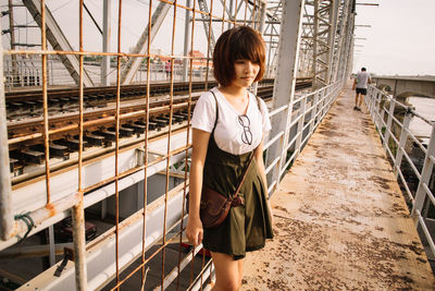 Portrait of young woman standing on railing