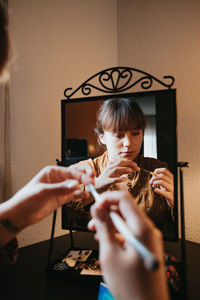 Woman holding make up brush in front of mirror