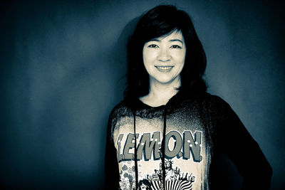 Portrait of smiling young woman standing against wall
