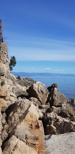 Rocks on beach against blue sky