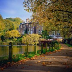 Empty footpath by canal in city during autumn