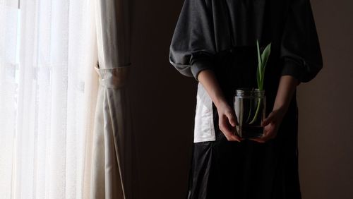 Midsection of man holding glass window at home