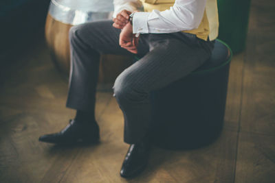 Low section of people sitting on hardwood floor at home