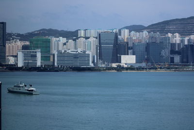 Scenic view of sea by city buildings against sky
