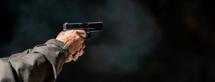 Cropped hand of man holding gun