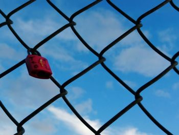 Low angle view of chainlink fence against blue sky