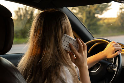 Young woman using mobile phone while sitting in car