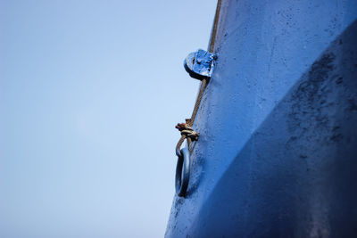 Low angle view of old metal door against clear blue sky