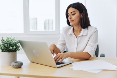 Portrait of businesswoman using laptop while sitting on table