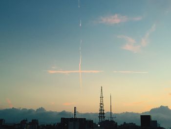 Wind turbines in city against sky during sunset