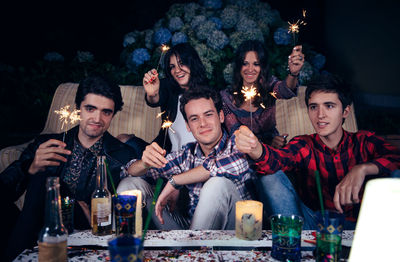 Young friends holding sparkler during party in backyard at night