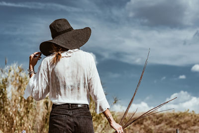 Rear view of woman standing on field against sky