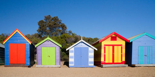 Multi colored hut on beach against clear blue sky