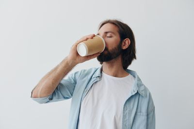 Young woman drinking milk against white background