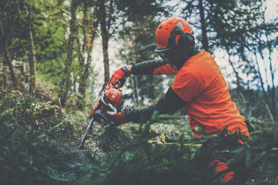 Man holding a chainsaw and cut trees. lumberjack at work gardener working outdoor in the forest.