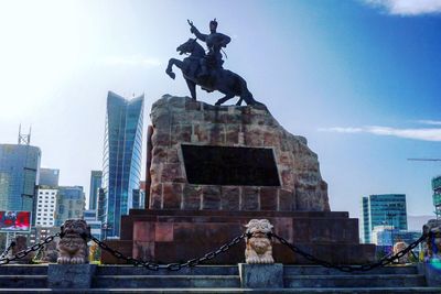 Statue in city against sky