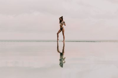 Full length of shirtless man on sea against sky