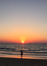 Silhouette person on shore against sky during sunset