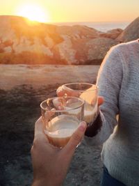 Midsection of woman holding drink against sky