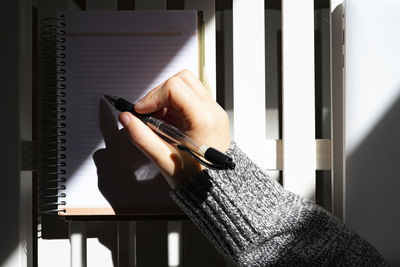 Woman writing on her calendar with a black pen.