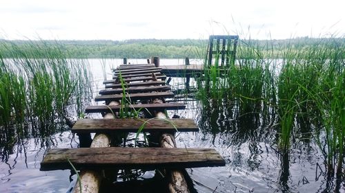 Wooden jetty in lake against sky