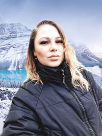 Portrait of beautiful woman standing on snow against mountains