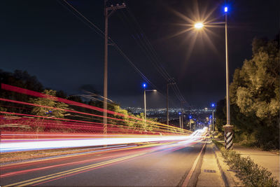 Light trails on road against sky at night