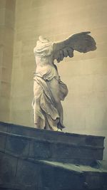 Low angle view of angel statue against wall