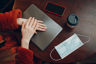 Midsection of woman sitting with laptop at table