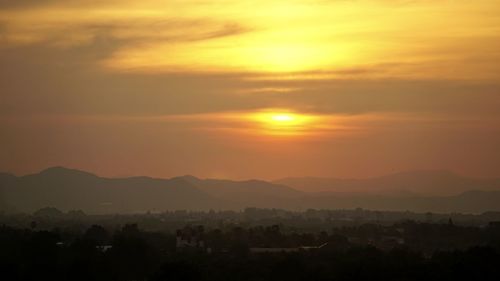 Scenic view of silhouette mountains against orange sky